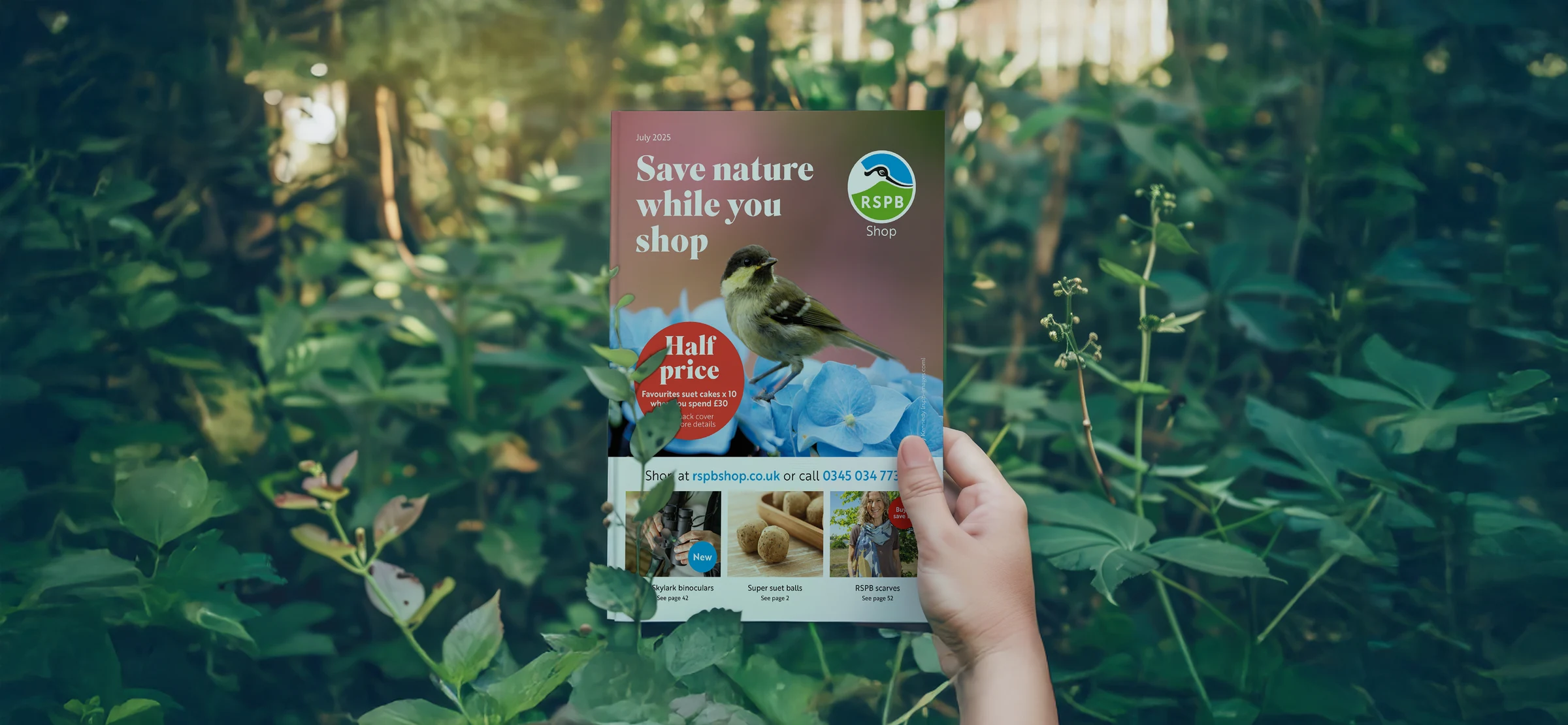 RSPB's shop catalogue held up in a garden, open to the July issue